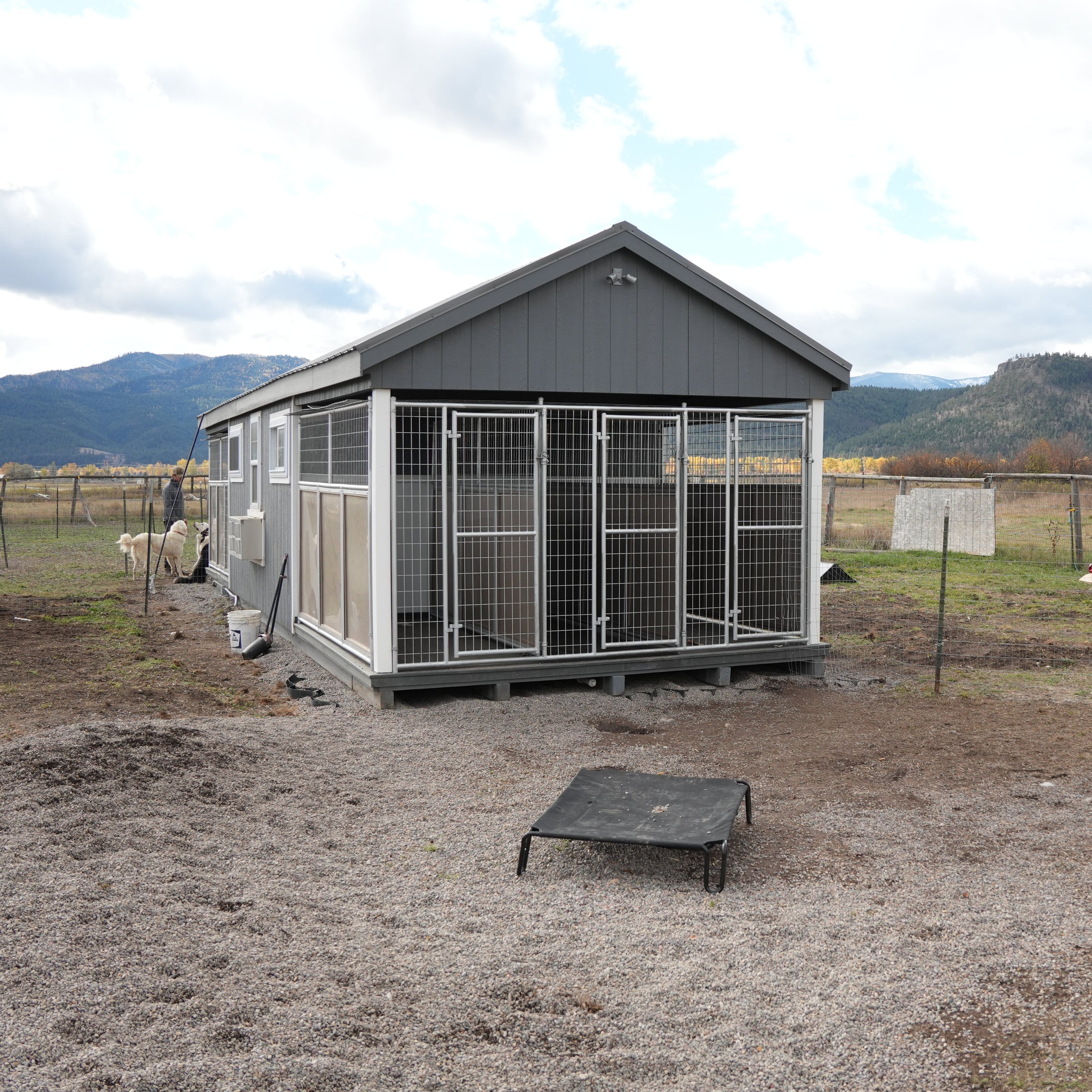Large outdoor animal enclosure with a metal roof and walls in a rural setting.